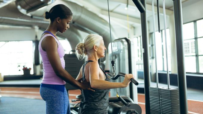 trainer assisting senior woman